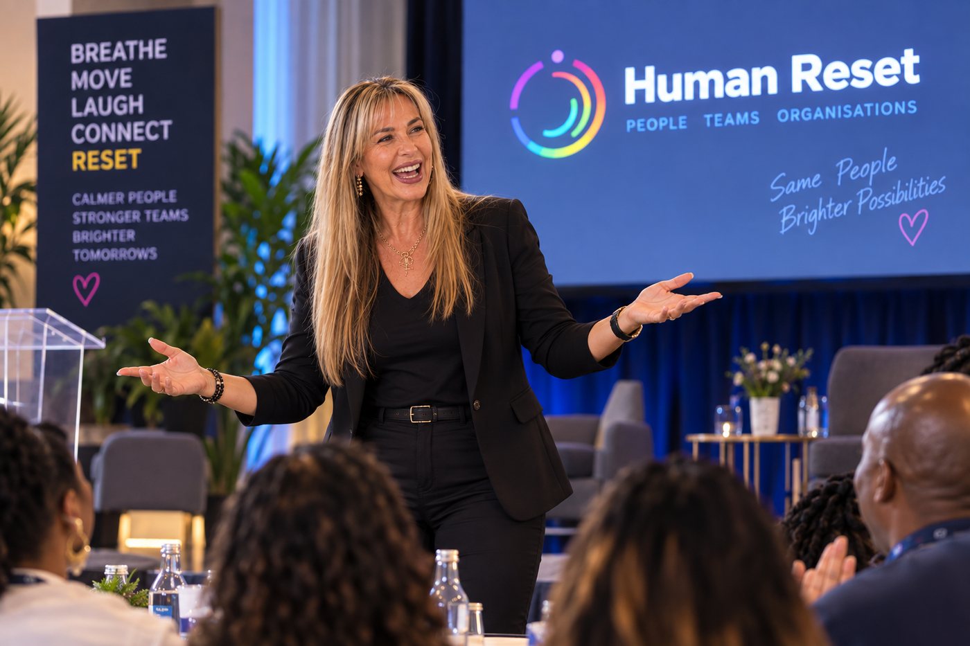 Shareen Richter speaking to a seated conference audience in front of the Human Reset screen