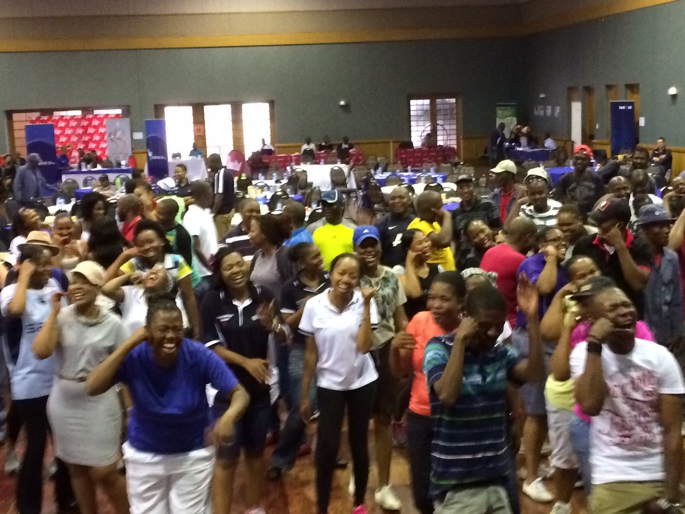 A packed hall of employees standing and laughing together